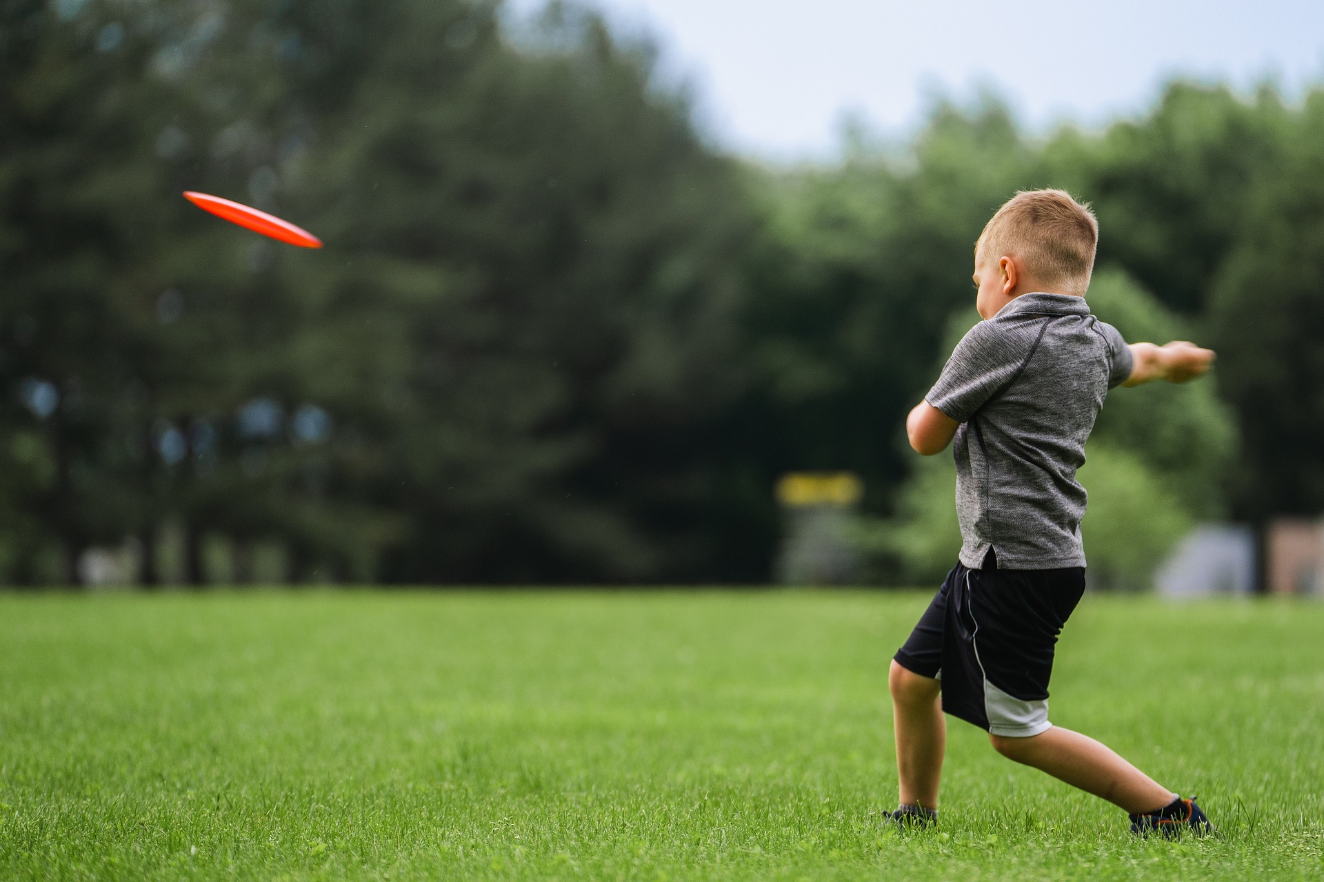 Junge wirft roten Frisbee 